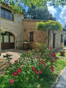 a stone house with roses in the yard at All'Ombra di San Damiano in Assisi