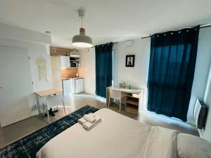a bedroom with a bed and a desk and a kitchen at We Live In R - Suite 401 in Reims