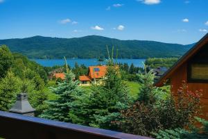 a balcony with a view of a house and a lake at BUENA VISTA POLAŃCZYK domki z klimatyzacją 506 - 289 - 019 in Polańczyk