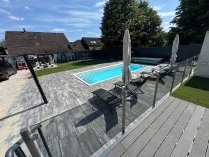 a swimming pool with two chairs and umbrellas next to at Bala-Home Apartments & Pool in Balatonboglár