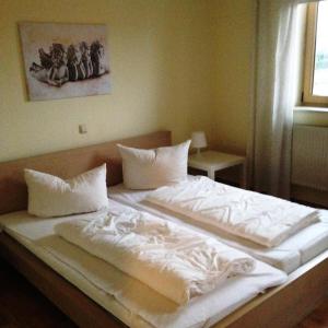 ein großes Bett mit weißer Bettwäsche und Kissen darauf in der Unterkunft Ferienhaus Emma in Zinnowitz