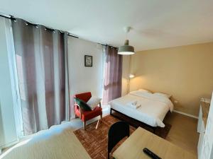 a bedroom with a bed and a chair and a table at We Live In R - Suite 103 in Reims +2 photos