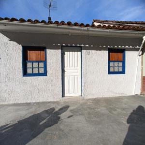 una persona parada frente a una casa blanca con una puerta en Lar, doce mar., en Paraty