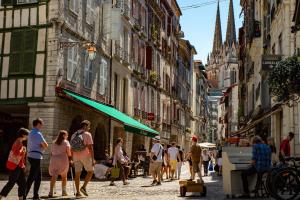 a group of people walking down a street with buildings at T1 à 10 min de l' océan in Boucau