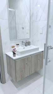 un bagno bianco con lavandino e specchio di Too Coool Apartment Mythical Seas 5 a Paralimni