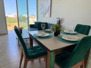 a dining room table with two plates and wine glasses at Too Coool 1 Bedroom Apartment Coralli Resort in Protaras
