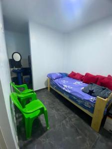 a bedroom with a bed and two green chairs at La casa del Panda in San Antonio