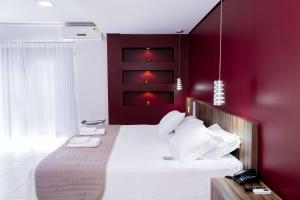 a bedroom with a large bed with red walls at Maison Hotel - Tangará da Serra in Tangara da Serra