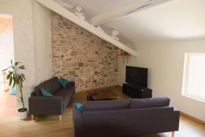 a living room with two couches and a stone wall at Maison de village provençale Mollans-Dru in Mollans-sur-Ouvèze