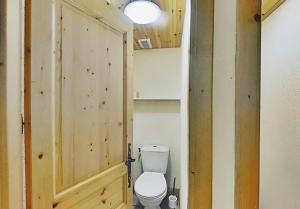 a bathroom with a toilet and a wooden door at Casa-Chalet du Merle N° 2 in Champagny-en-Vanoise +34 photos