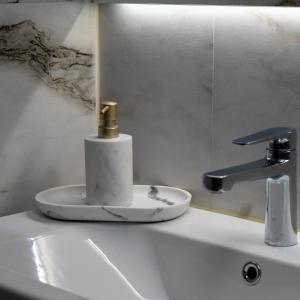 a bathroom sink with a gold soap dispenser on it at Stone House Bran in Tohanu Nou +14 photos