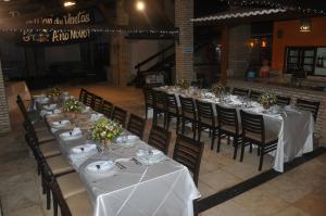 a long table with white tables and chairs with flowers at Fazenda Hotel Pedra dos Ventos in Quixadá