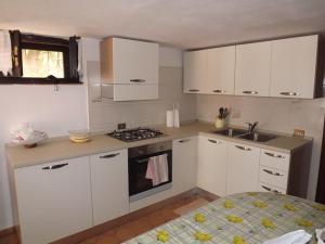 a kitchen with white cabinets and a sink and a stove at Relax a Calasapone in SantʼAntìoco