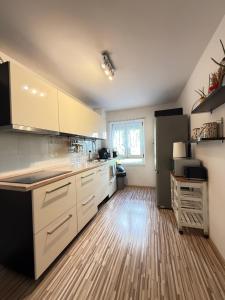 una cucina con mobili bianchi e pavimento in legno di Ferienwohnung Hügelstraße a Wuppertal