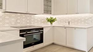 a white kitchen with a stove and a sink at Private Villa Houlakia Mikonos in Agios Stefanos