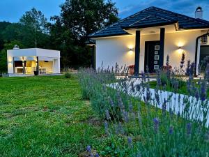 a house with a garden with purple flowers in front of it at Mali Raj in Banja