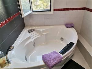 a white tub in a bathroom with a purple towel at Jimmy's Romantic Getaway in Egina