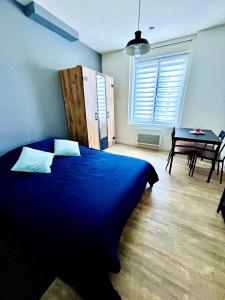 a bedroom with a blue bed and a table at Studio Escale - Coeur de ville in Gravelines