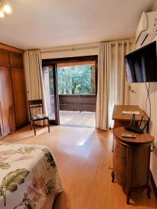 ein Schlafzimmer mit einem Bett, einem Schreibtisch und einem Fernseher in der Unterkunft Casa Allegro 3dorm prox Lago Negro by AcheiGramado in Gramado