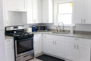 a white kitchen with a stove and a sink at Sojourn on the Bay 2 BR Private Beach Access in Norfolk +64 photos