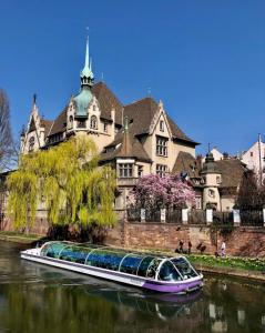 シルティカイムにあるLa Résidence St Arnould, À 10 min du centre de Strasbourgの大きな建物の前の川上船