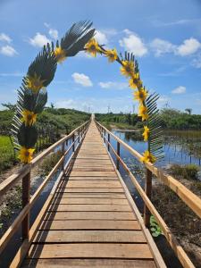 a wooden bridge over a river with flowers on it at Pousada Brisa das Dunas in Paulino Neves +37 photos