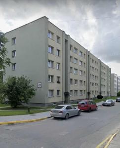 a large white building with cars parked in a parking lot at Namų mūza "A" SELF CHECK IN in Plungė