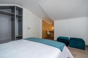 een slaapkamer met een bed en twee blauwe stoelen bij Barreiro View in Ribeira Brava