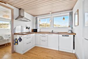 a kitchen with white cabinets and two windows at 503-Hvide-Sande-Sonder-Klitvej-129 in Havrvig