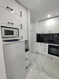 a kitchen with white cabinets and a microwave at Apartament Premium Tarnów 2 in Tarnów