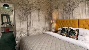a bedroom with a large bed and trees on the wall at Atholl Arms Hotel Dunkeld in Dunkeld