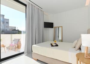 ein weißes Schlafzimmer mit Bett und Balkon in der Unterkunft Kalma Luxury Living Suites Heraklion in Iraklio
