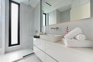 ein weißes Badezimmer mit Waschbecken und Spiegel in der Unterkunft Kalma Luxury Living Suites Heraklion in Iraklio + 31 Fotos