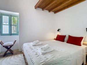 a bedroom with a bed with red pillows and a chair at Casa Martim in Romão