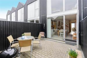 a patio with a table and chairs and a building at 717-Hvide-Sande-Slusen-17 in Hvide Sande