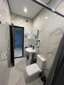 a white bathroom with a toilet and a sink at Saba Guest House in Ureki
