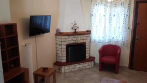 a living room with a fireplace with a television and a chair at Dasea Houses in Ormos Panagias