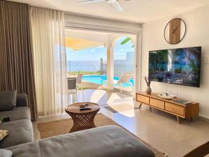 弗利康弗拉克Solara West - Private Pool and Seafront的带沙发和电视的客厅以及游泳池。