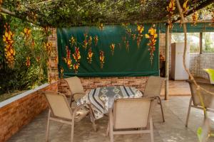 a table and chairs on a patio with a green screen at Pousada Capão da Coruja in Santa Bárbara