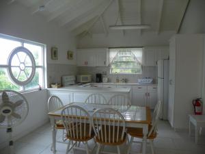 a kitchen with a table and chairs and a refrigerator at AnnJenn Apartments in Christ Church