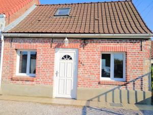 a brick house with a white door and two windows at Maison Le Wetz Calme, Confort in Sainte-Marie-Kerque