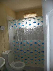 a bathroom with a toilet and a shower curtain with fish at AnnJenn Apartments in Christ Church