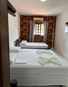 a bedroom with three beds and a window at Pousada Praiana Pipa in Pipa