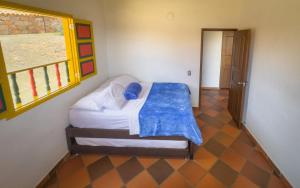a bedroom with a bed with a blue blanket on it at Hacienda El Encanto in Los Santos