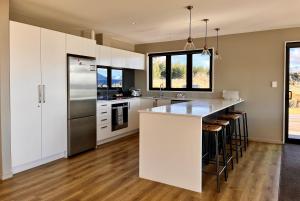 a kitchen with white cabinets and a stainless steel refrigerator at Starview 88 - Lake Tekapo in Lake Tekapo