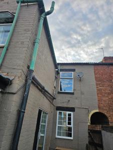 a green pipe on the side of a building at Centrally located house, Rm 4 big in Burton upon Trent