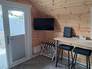 a wooden room with a desk and a tv on a wall at Beinn View Pod in Corpach