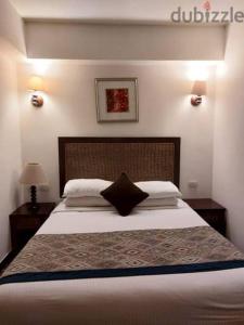 a bedroom with a large bed with a black pillow at porto south beach from amer group شاليه فندقى من عامر جروب فى بورتو ساوث بيتش منطقه التايم شير المميزه in Ain Sokhna