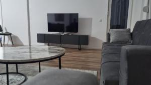 a living room with a couch and a table and a tv at Etno apartmemt in Prishtinë