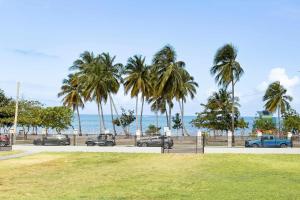 un parc avec des palmiers et l'océan en arrière-plan dans l'établissement Fully Renovated Beachfront 2 Bedroom Unit 4 1 Bath Prime Dorado Location, à Dorado